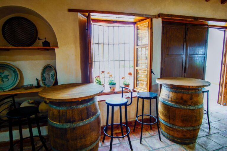 Interior de casa rural transformada en lugar de reuniones, con barriles y silletines altos para tomar algo