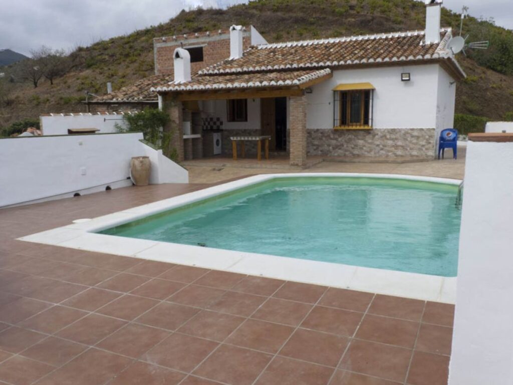 Fachada de casa rural típica de la Axarquía, con porche y piscina delante