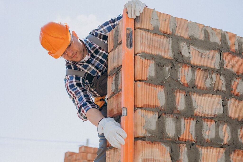 Albañil poniendo el nivel a pared de ladrillos recién construida