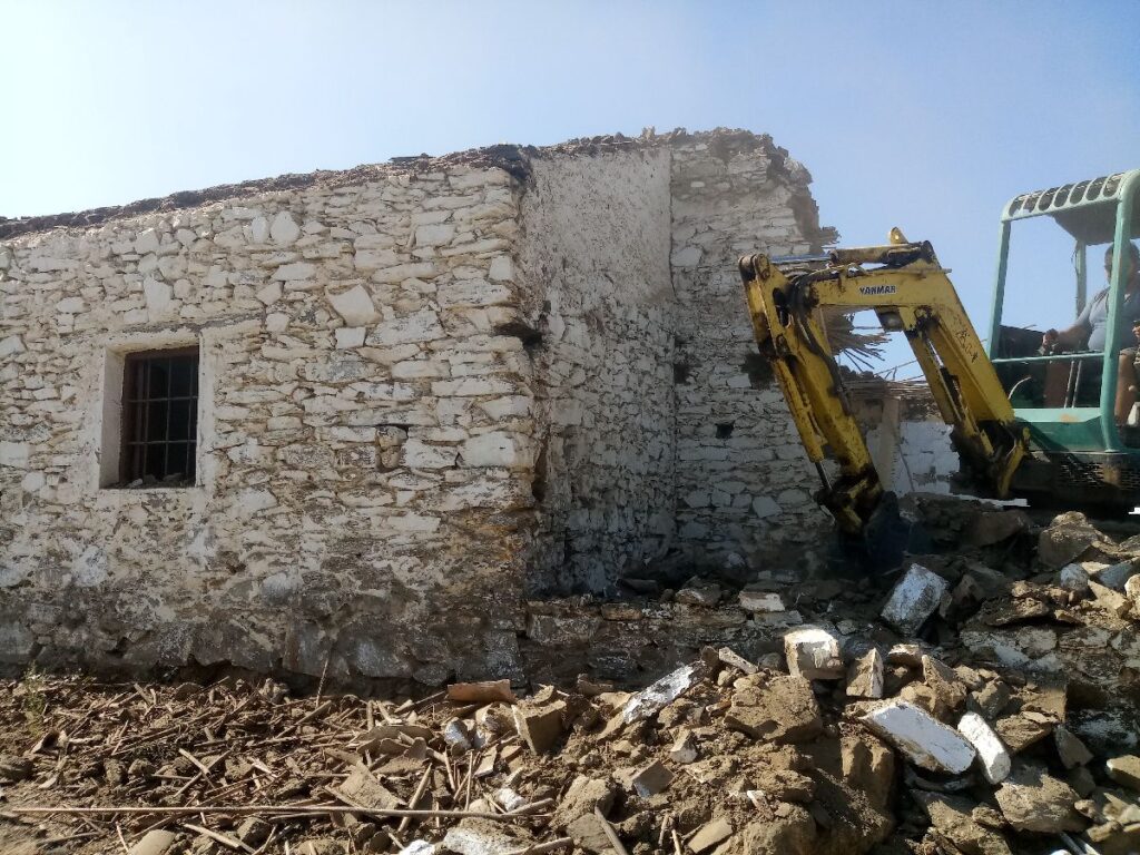 Ruina de casa antigua de piedra siendo demolida con maquinaria de demolición